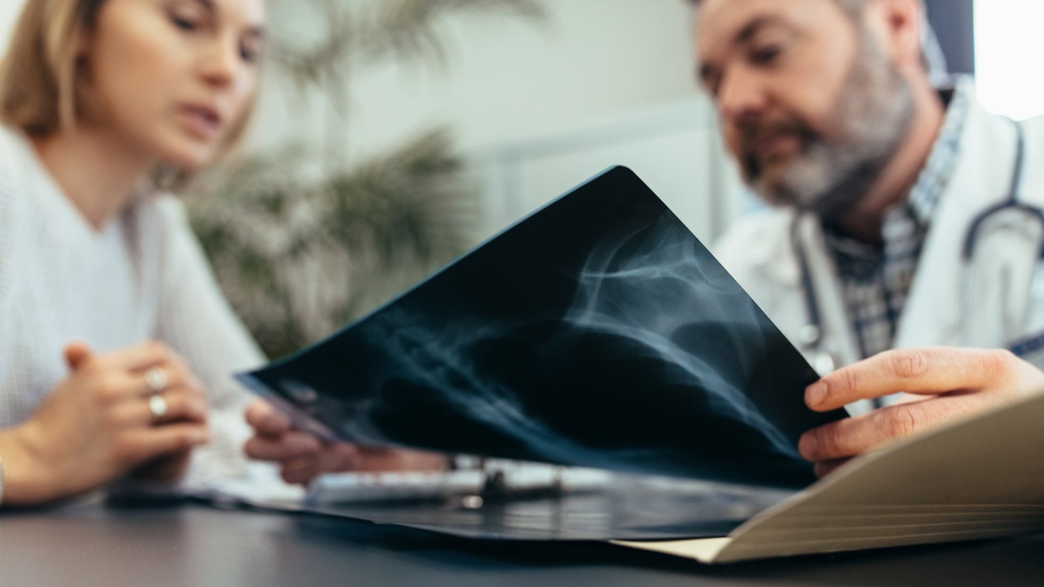 Læge og kvinde sidder ved et bord og kigger på et røgtenbillede.