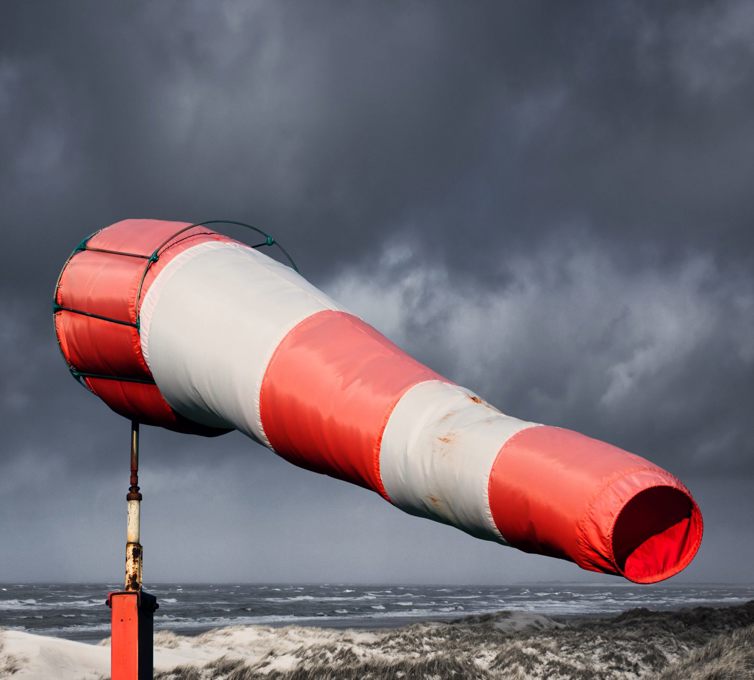 Rød og hvid vindpose på stranden, hvor der er sort himmel.