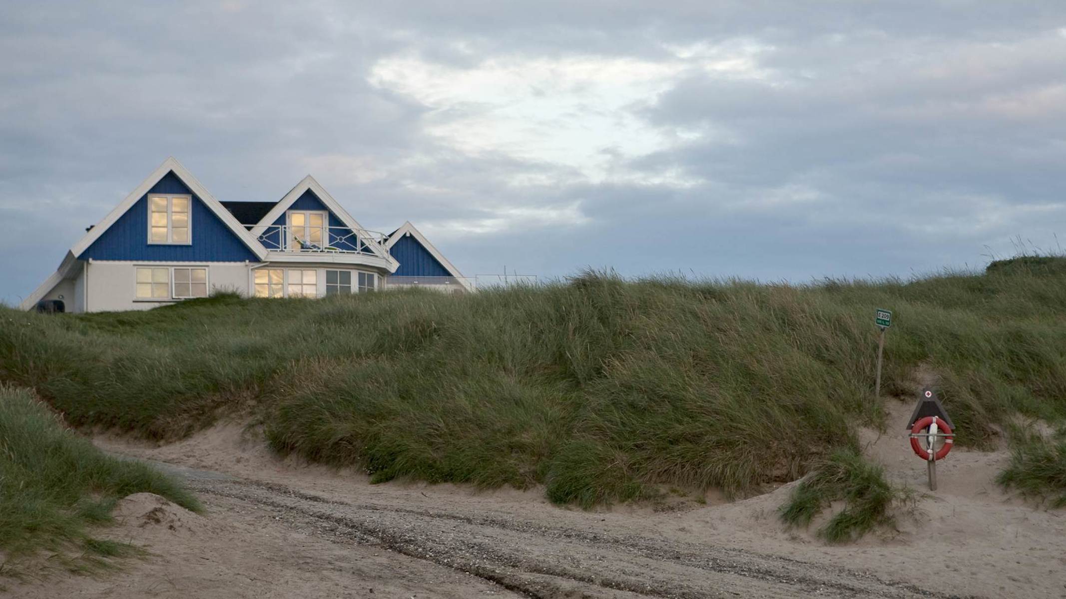 Hvidt og blåt sommerhus på strand.