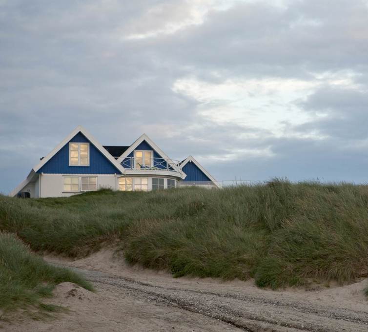 Hvidt og blåt sommerhus på strand.