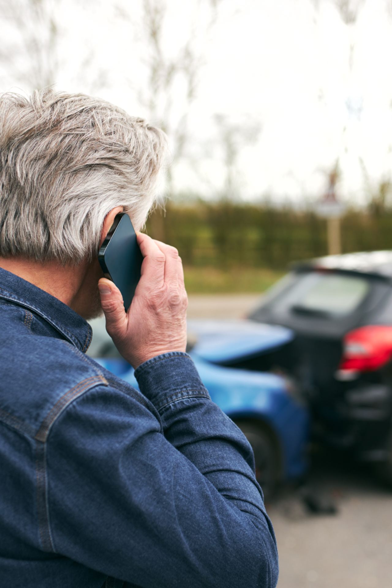 Mand taler i telefon foran to biler, der er kørt sammen.